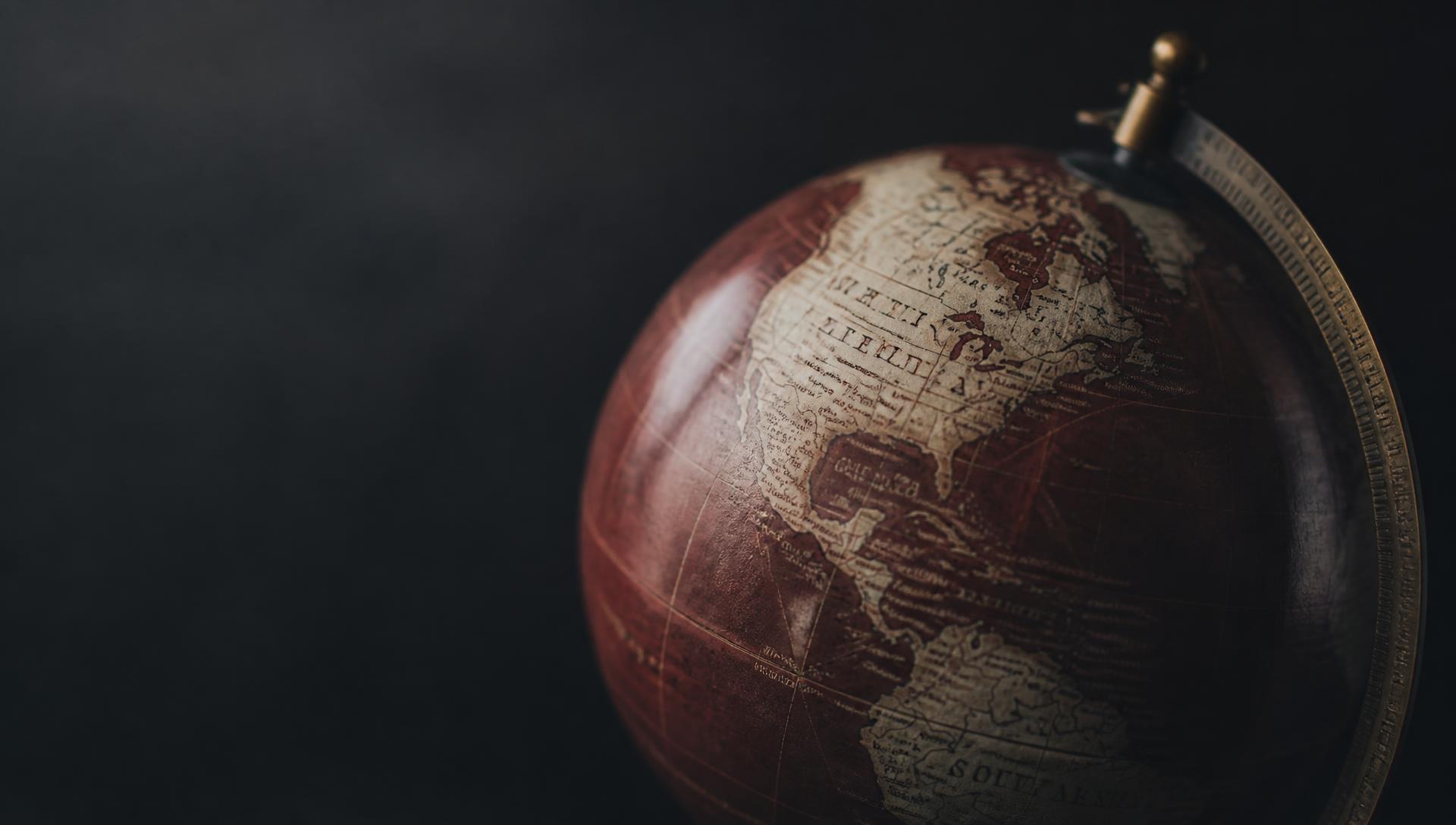 Close-up of a vintage desk globe in burgundy tones against a dark background